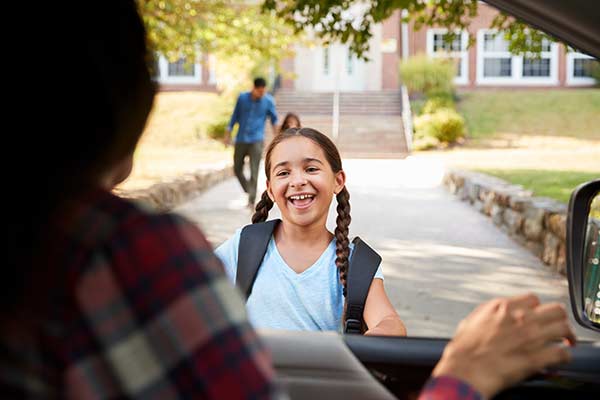 Girl approaching car from school to be picked up